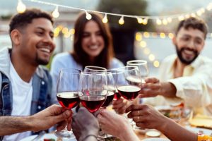 Group,Of,Young,People,Toasting,Red,Wine,At,Rooftop,Night