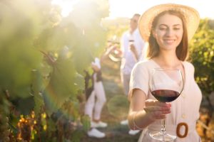 Beautiful,Young,Woman,With,Glass,Of,Wine,In,Vineyard,,Focus
